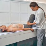 Exhausted female person lying on the couch and doing stretching exercise on leg
